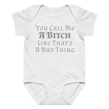 "You Call Me A Bitch Like That's A Bad Thing" printed on a ash baby jersey bodysuit laying on a flat surface amongst other clothes