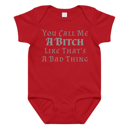 "You Call Me A Bitch Like That's A Bad Thing" printed on a red baby jersey bodysuit laying on a flat surface amongst other clothes