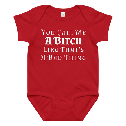 "You Call Me A Bitch Like That's A Bad Thing" printed on a red baby jersey bodysuit laying on a flat surface amongst other clothes