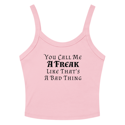 "You Call Me A Freak Like That's A Bad Thing" printed on a solid pink blend women's micro-rib tanktop laying on a flat surface amongst sunglasses and shorts