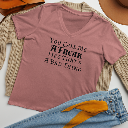 "You Call Me A Freak Like That's A Bad Thing" printed on a heather mauve women's relaxed v-neck t-shirt laying on a flat surface amongst other clothes