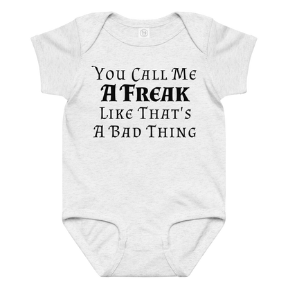 "You Call Me A Freak Like That's A Bad Thing" printed on a ash baby jersey bodysuit laying on a flat surface amongst other clothes