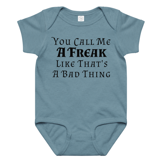 "You Call Me A Freak Like That's A Bad Thing" printed on a vintage indigo baby jersey bodysuit laying on a flat surface amongst other clothes