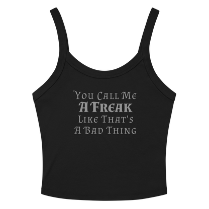 "You Call Me A Freak Like That's A Bad Thing" printed on a solid black blend women's micro-rib tanktop laying on a flat surface amongst sunglasses and shorts