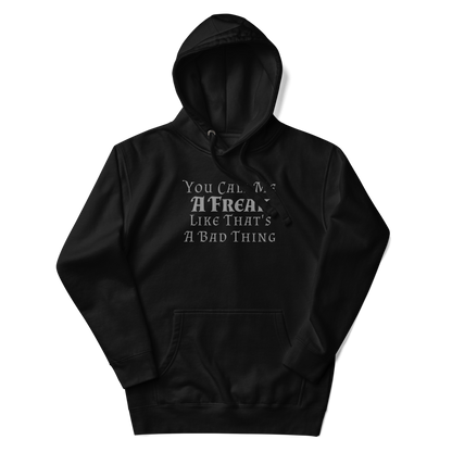 "You Call Me A Freak Like That's A Bad Thing" printed on a black unisex hoodie laying on a flat surface with the hood up