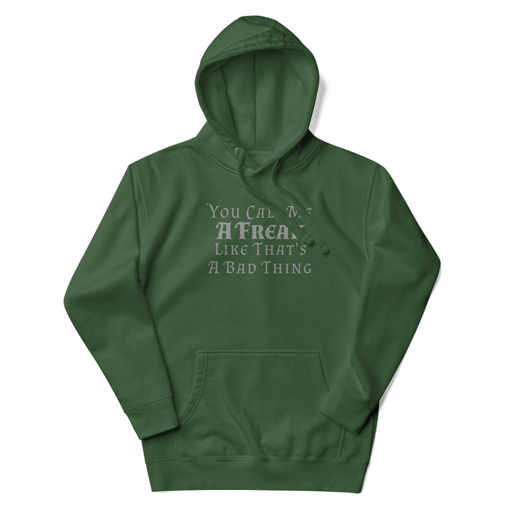 "You Call Me A Freak Like That's A Bad Thing" printed on a forest green unisex hoodie laying on a flat surface with the hood up