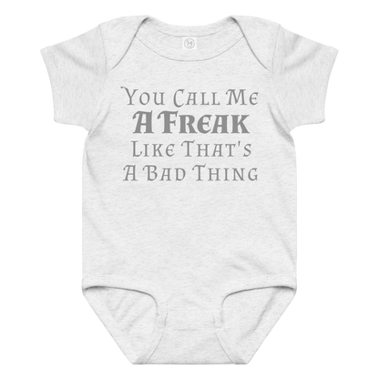 "You Call Me A Freak Like That's A Bad Thing" printed on a ash baby jersey bodysuit laying on a flat surface amongst other clothes