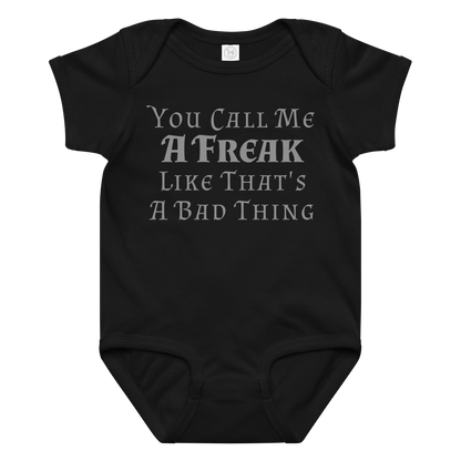 "You Call Me A Freak Like That's A Bad Thing" printed on a black baby jersey bodysuit laying on a flat surface amongst other clothes