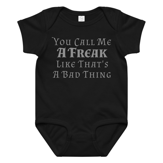 "You Call Me A Freak Like That's A Bad Thing" printed on a black baby jersey bodysuit laying on a flat surface amongst other clothes