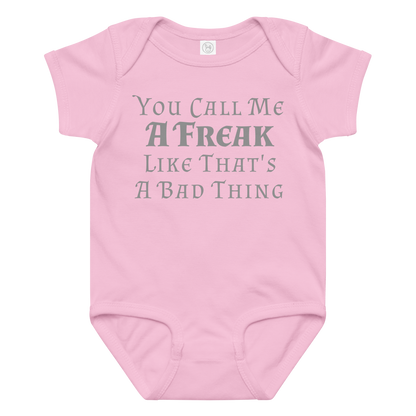 "You Call Me A Freak Like That's A Bad Thing" printed on a pink baby jersey bodysuit laying on a flat surface amongst other clothes