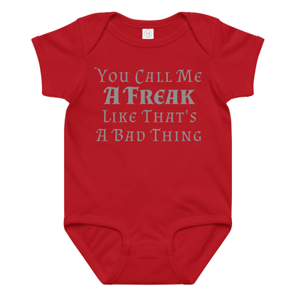 "You Call Me A Freak Like That's A Bad Thing" printed on a red baby jersey bodysuit laying on a flat surface amongst other clothes
