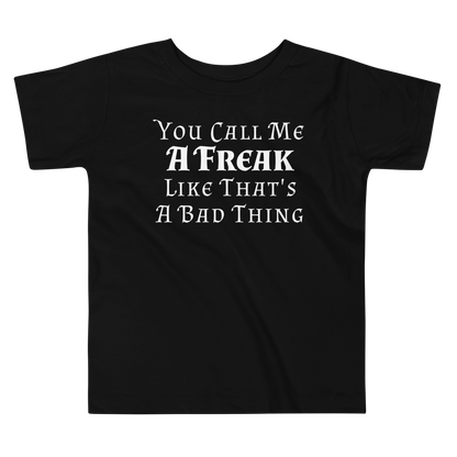 "You Call Me A Freak Like That's A Bad Thing" printed on a black toddler short sleeve tee laying on a flat surface