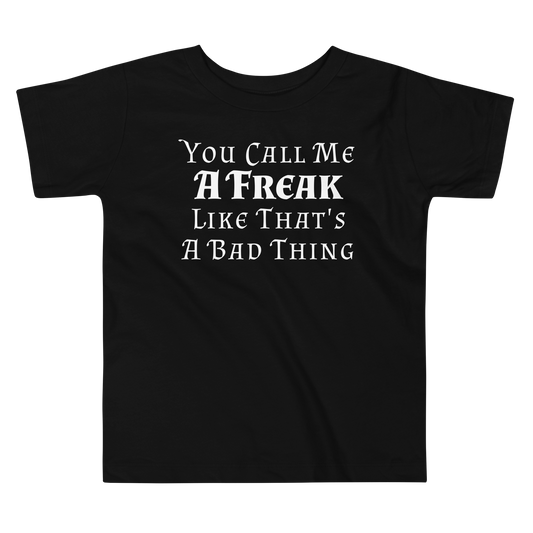 "You Call Me A Freak Like That's A Bad Thing" printed on a black toddler short sleeve tee laying on a flat surface