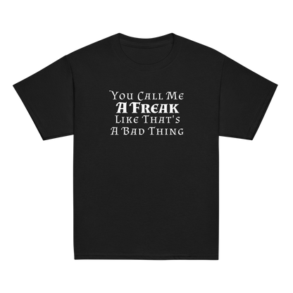 "You Call Me A Freak Like That's A Bad Thing" printed on a black youth classic tee laying on a flat surface