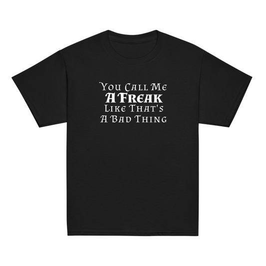 "You Call Me A Freak Like That's A Bad Thing" printed on a black youth classic tee laying on a flat surface
