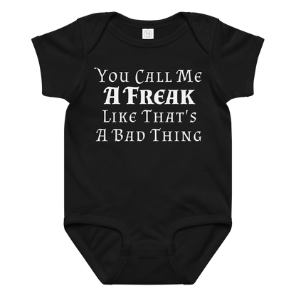 "You Call Me A Freak Like That's A Bad Thing" printed on a black baby jersey bodysuit laying on a flat surface amongst other clothes