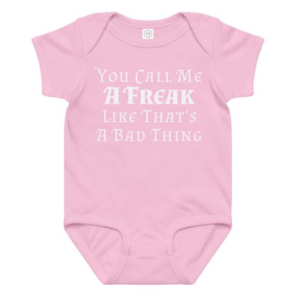 "You Call Me A Freak Like That's A Bad Thing" printed on a pink baby jersey bodysuit laying on a flat surface amongst other clothes
