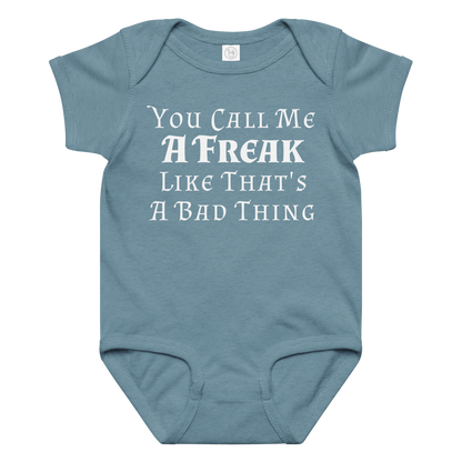 "You Call Me A Freak Like That's A Bad Thing" printed on a vintage indigo baby jersey bodysuit laying on a flat surface amongst other clothes
