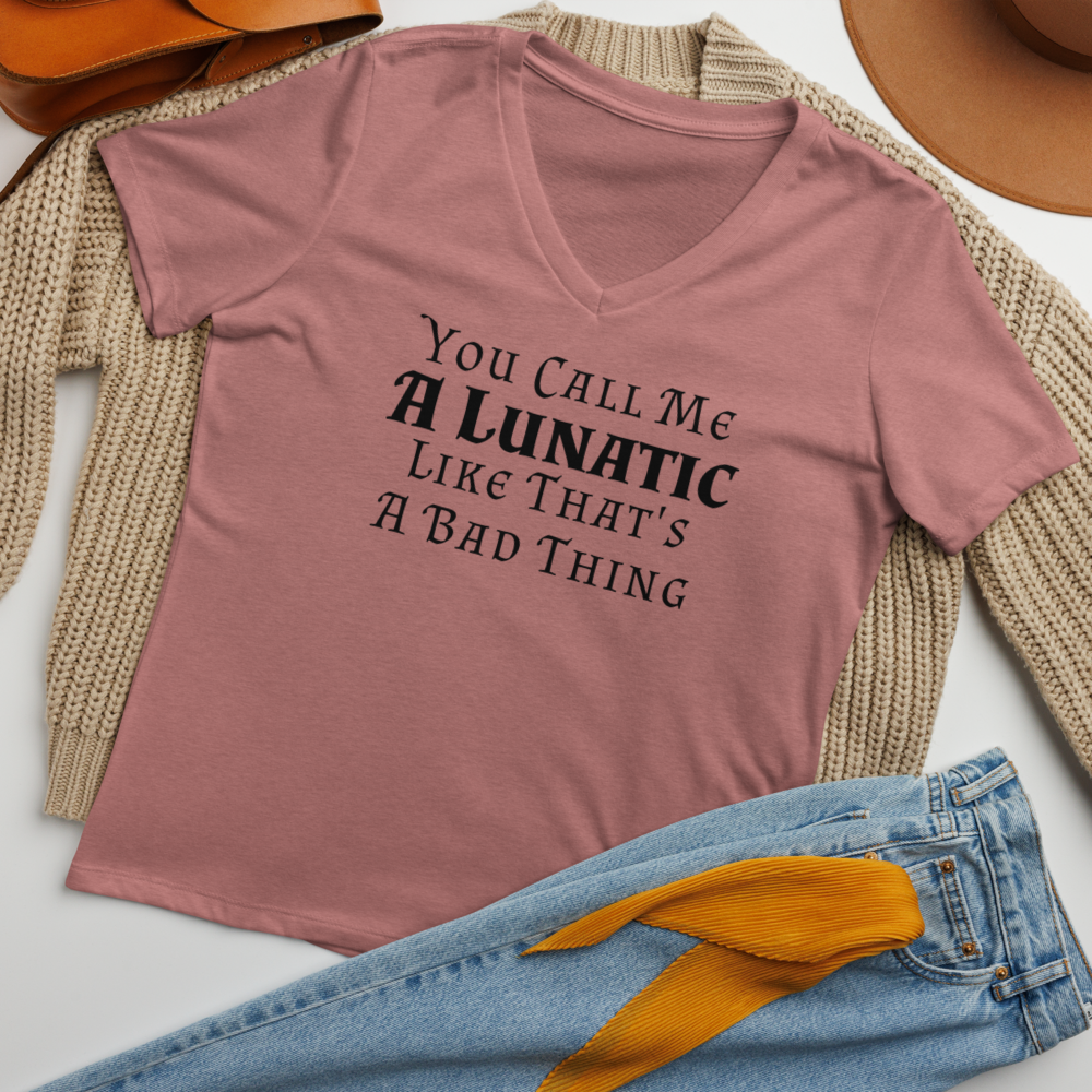 "You Call Me A Lunatic Like That's A Bad Thing" printed on a heather mauve women's relaxed v-neck t-shirt laying on a flat surface amongst other clothes