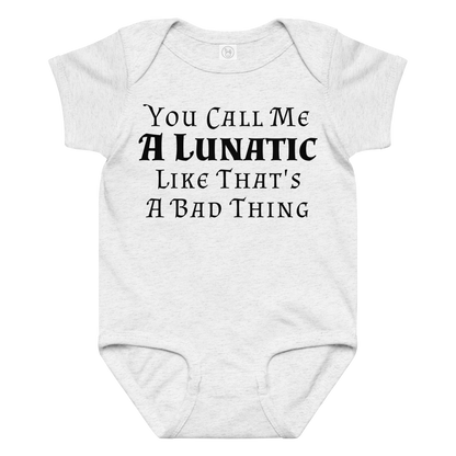 "You Call Me A Lunatic Like That's A Bad Thing" printed on a ash baby jersey bodysuit laying on a flat surface amongst other clothes