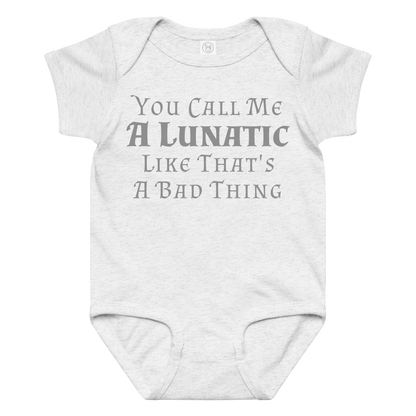 "You Call Me A Lunatic Like That's A Bad Thing" printed on a ash baby jersey bodysuit laying on a flat surface amongst other clothes