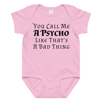 "You Call Me A Psycho Like That's A Bad Thing" printed on a pink baby jersey bodysuit laying on a flat surface amongst other clothes