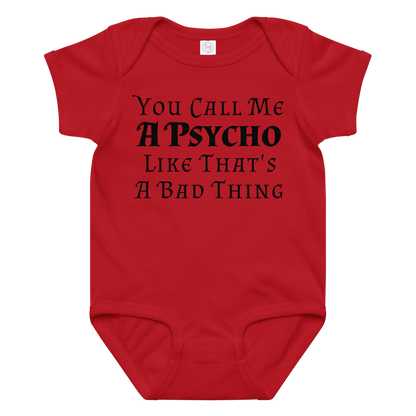 "You Call Me A Psycho Like That's A Bad Thing" printed on a red baby jersey bodysuit laying on a flat surface amongst other clothes