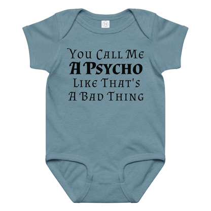 "You Call Me A Psycho Like That's A Bad Thing" printed on a vintage indigo baby jersey bodysuit laying on a flat surface amongst other clothes