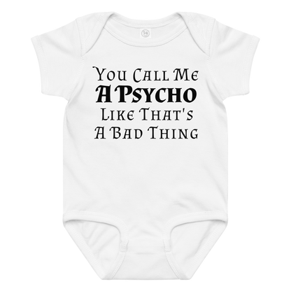 "You Call Me A Psycho Like That's A Bad Thing" printed on a white baby jersey bodysuit laying on a flat surface amongst other clothes