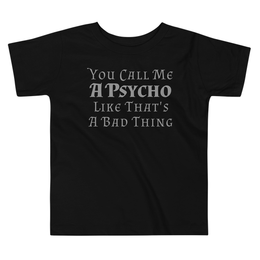 "You Call Me A Psycho Like That's A Bad Thing" printed on a black toddler short sleeve tee laying on a flat surface