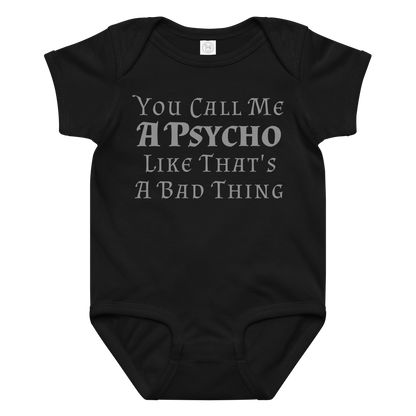 "You Call Me A Psycho Like That's A Bad Thing" printed on a black baby jersey bodysuit laying on a flat surface amongst other clothes