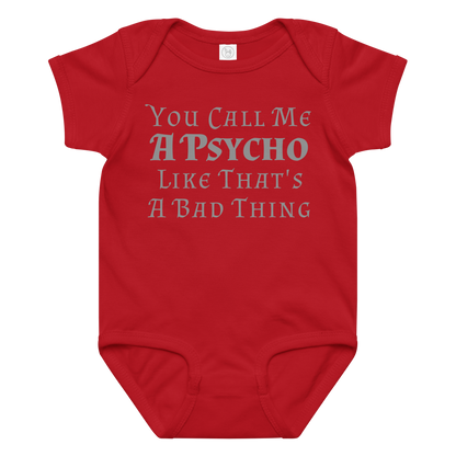 "You Call Me A Psycho Like That's A Bad Thing" printed on a red baby jersey bodysuit laying on a flat surface amongst other clothes