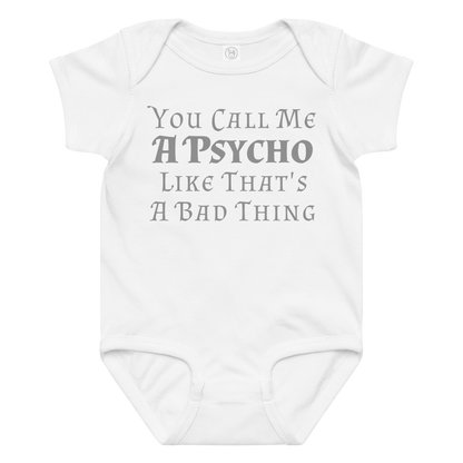 "You Call Me A Psycho Like That's A Bad Thing" printed on a white baby jersey bodysuit laying on a flat surface amongst other clothes