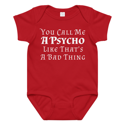 "You Call Me A Psycho Like That's A Bad Thing" printed on a red baby jersey bodysuit laying on a flat surface amongst other clothes