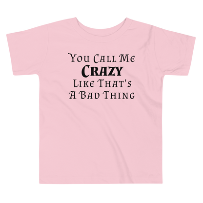 "You Call Me Crazy Like That's A Bad Thing" printed on a pink toddler short sleeve tee laying on a flat surface