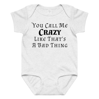 "You Call Me Crazy Like That's A Bad Thing" printed on a ash baby jersey bodysuit laying on a flat surface amongst other clothes