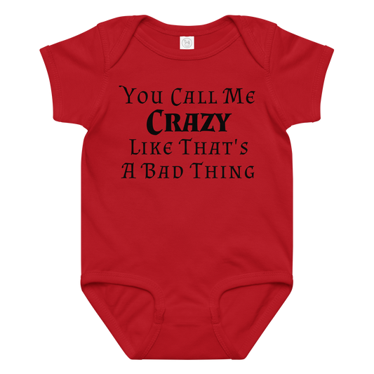 "You Call Me Crazy Like That's A Bad Thing" printed on a red baby jersey bodysuit laying on a flat surface amongst other clothes