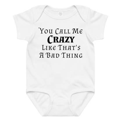 "You Call Me Crazy Like That's A Bad Thing" printed on a white baby jersey bodysuit laying on a flat surface amongst other clothes