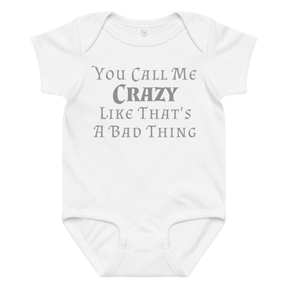 "You Call Me Crazy Like That's A Bad Thing" printed on a white baby jersey bodysuit laying on a flat surface amongst other clothes