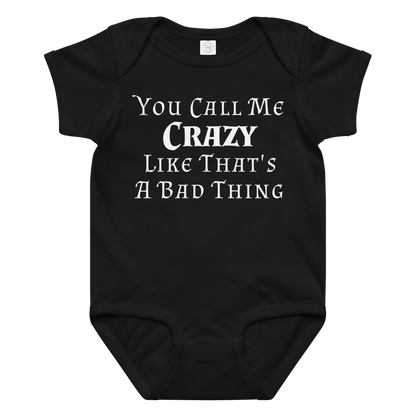 "You Call Me Crazy Like That's A Bad Thing" printed on a black baby jersey bodysuit laying on a flat surface amongst other clothes