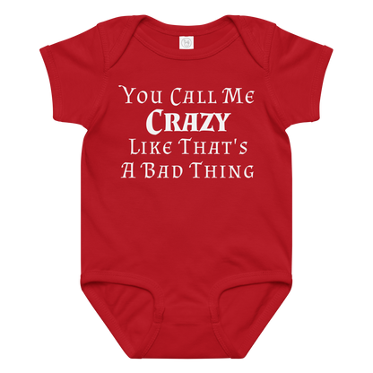 "You Call Me Crazy Like That's A Bad Thing" printed on a red baby jersey bodysuit laying on a flat surface amongst other clothes