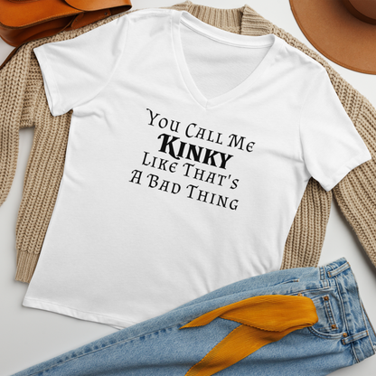 "You Call Me Kinky Like That's A Bad Thing" printed on a solid white blend women's relaxed v-neck t-shirt laying on a flat surface amongst other clothes