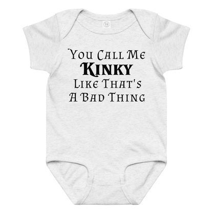 "You Call Me Kinky Like That's A Bad Thing" printed on a ash baby jersey bodysuit laying on a flat surface amongst other clothes