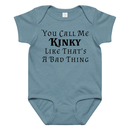 "You Call Me Kinky Like That's A Bad Thing" printed on a vintage indigo baby jersey bodysuit laying on a flat surface amongst other clothes