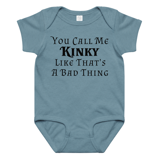 "You Call Me Kinky Like That's A Bad Thing" printed on a vintage indigo baby jersey bodysuit laying on a flat surface amongst other clothes