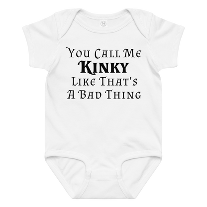 "You Call Me Kinky Like That's A Bad Thing" printed on a white baby jersey bodysuit laying on a flat surface amongst other clothes