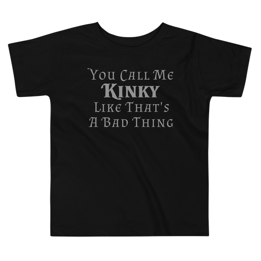 "You Call Me Kinky Like That's A Bad Thing" printed on a black toddler short sleeve tee laying on a flat surface