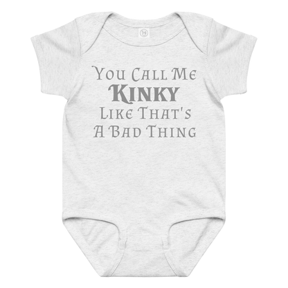 "You Call Me Kinky Like That's A Bad Thing" printed on a ash baby jersey bodysuit laying on a flat surface amongst other clothes