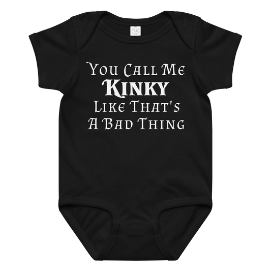 "You Call Me Kinky Like That's A Bad Thing" printed on a black baby jersey bodysuit laying on a flat surface amongst other clothes