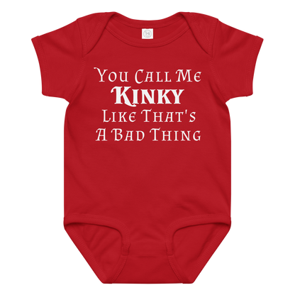 "You Call Me Kinky Like That's A Bad Thing" printed on a red baby jersey bodysuit laying on a flat surface amongst other clothes
